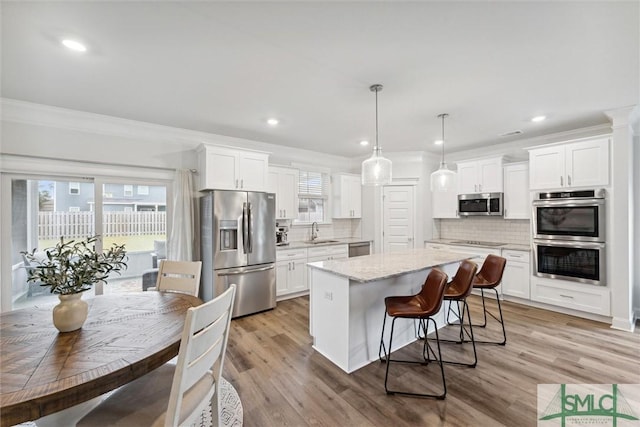 kitchen featuring a center island, white cabinetry, stainless steel appliances, and tasteful backsplash