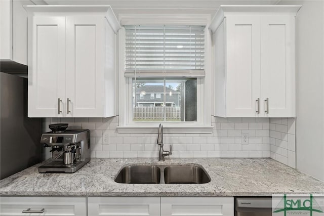 kitchen featuring backsplash, light stone counters, white cabinetry, and sink