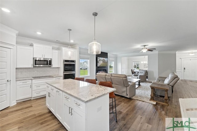 kitchen with white cabinets, decorative light fixtures, a center island, and stainless steel appliances