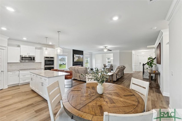 dining area featuring ceiling fan, ornamental molding, and light hardwood / wood-style flooring