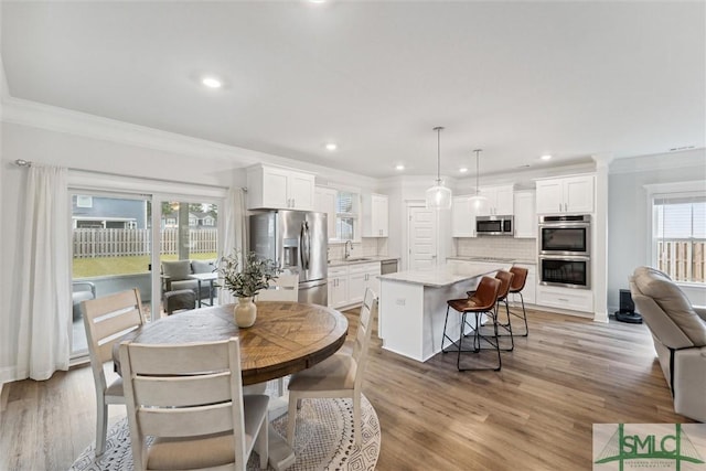 dining area featuring light hardwood / wood-style floors, ornamental molding, and sink