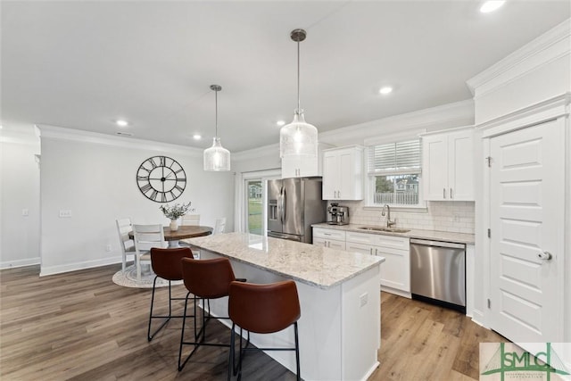 kitchen featuring white cabinets, stainless steel appliances, a kitchen island, and sink