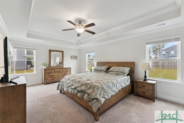 bedroom featuring light carpet, a tray ceiling, ceiling fan, and crown molding