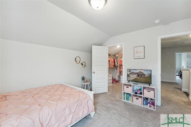 bedroom with a spacious closet, a closet, light colored carpet, and lofted ceiling