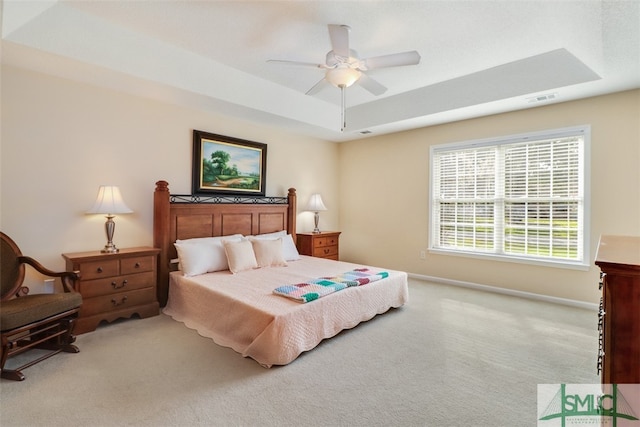 carpeted bedroom featuring ceiling fan and a tray ceiling