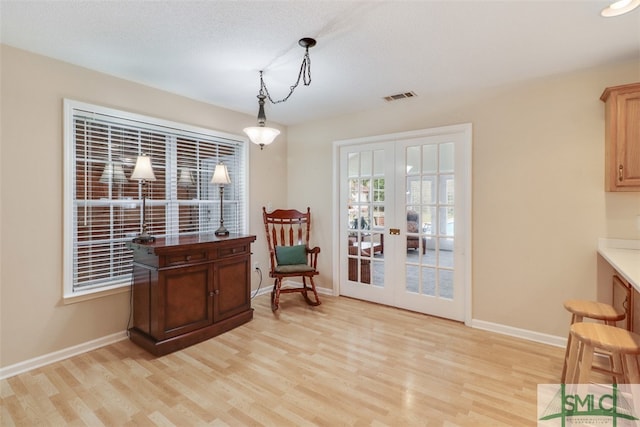 sitting room featuring french doors, light hardwood / wood-style floors, and a textured ceiling