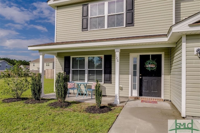 entrance to property featuring a lawn and a porch