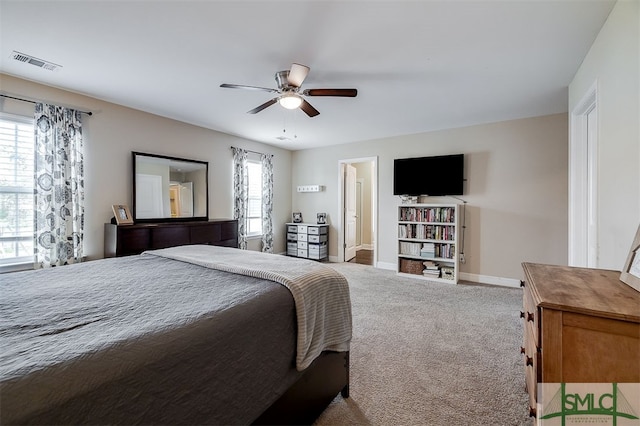 carpeted bedroom with ceiling fan, connected bathroom, and multiple windows