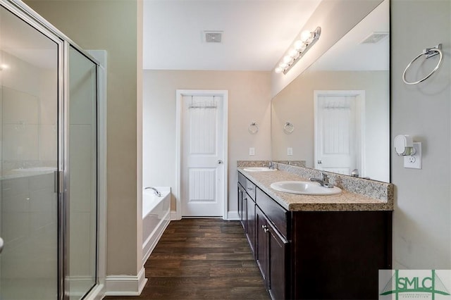 bathroom with a bath, a stall shower, wood finished floors, and a sink