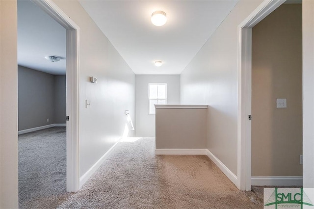 corridor with baseboards, an upstairs landing, and carpet flooring