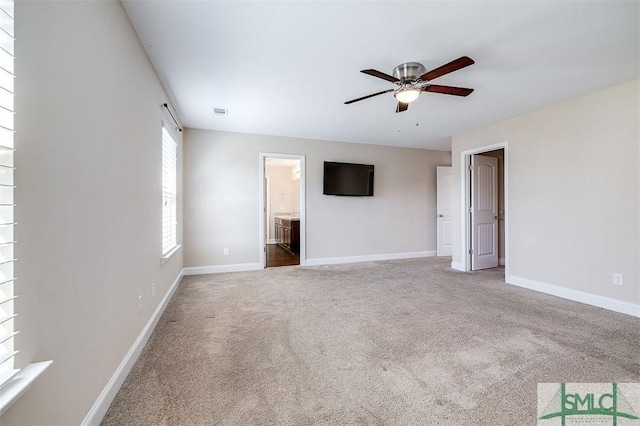 interior space featuring carpet flooring, ceiling fan, connected bathroom, and baseboards