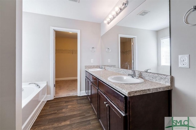 bathroom featuring a spacious closet, wood finished floors, visible vents, and a sink