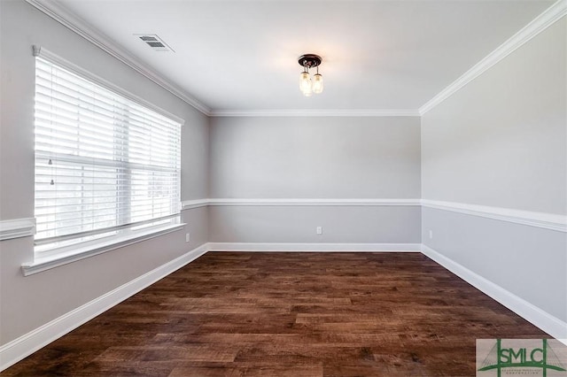 empty room with crown molding, wood finished floors, baseboards, and visible vents