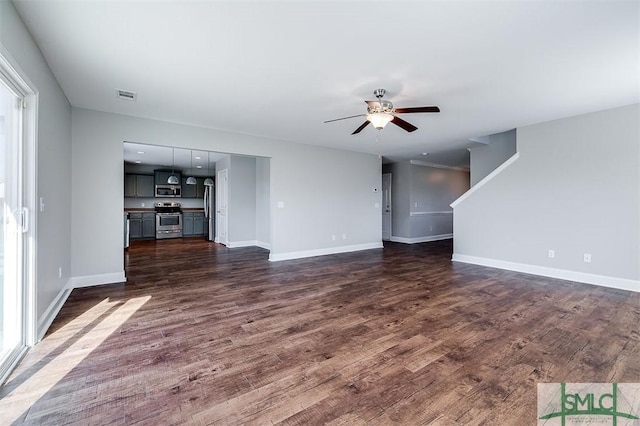 unfurnished living room featuring dark wood-style floors, visible vents, baseboards, and a ceiling fan