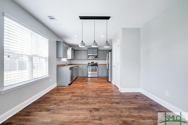 kitchen featuring visible vents, gray cabinets, a sink, dark wood-style floors, and stainless steel appliances