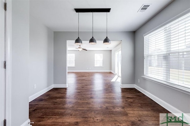 unfurnished dining area featuring ceiling fan, dark wood-style floors, visible vents, and baseboards