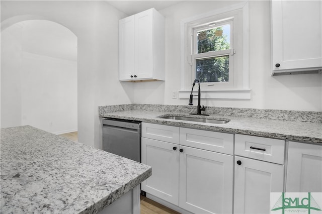 kitchen with light stone countertops, dishwasher, sink, light hardwood / wood-style floors, and white cabinets