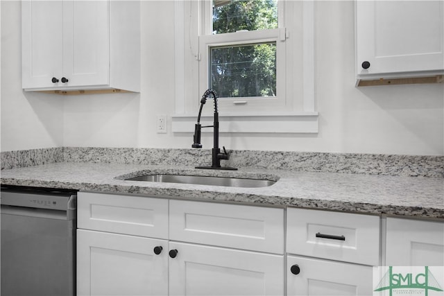 kitchen with dishwasher, white cabinetry, and sink