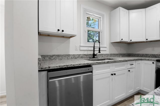 kitchen with sink, light stone counters, light hardwood / wood-style flooring, stainless steel dishwasher, and white cabinets