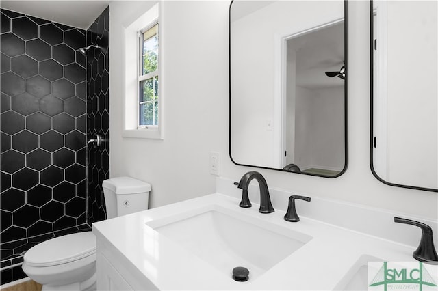 bathroom featuring a tile shower, vanity, and toilet