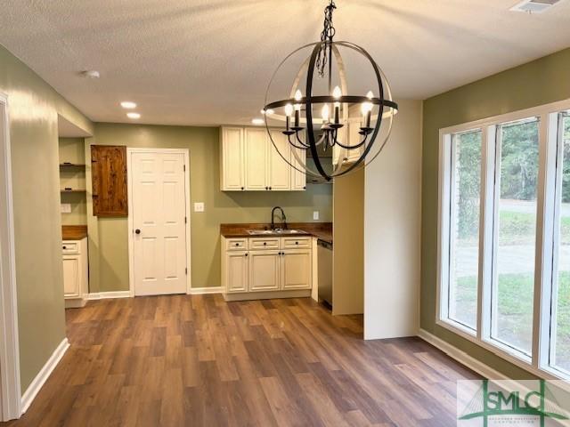 kitchen featuring dark hardwood / wood-style flooring, a textured ceiling, sink, an inviting chandelier, and dishwasher