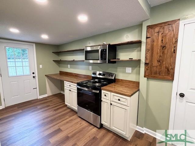 kitchen with white cabinetry, dark hardwood / wood-style flooring, appliances with stainless steel finishes, and wood counters