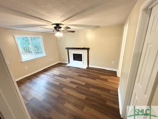 unfurnished living room featuring a fireplace, a textured ceiling, dark hardwood / wood-style flooring, and ceiling fan