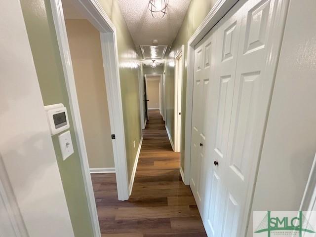 corridor featuring dark hardwood / wood-style flooring and a textured ceiling