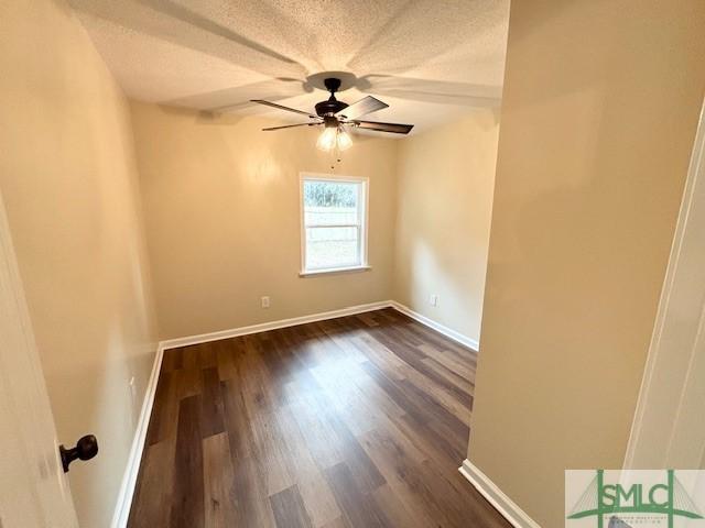 unfurnished room with ceiling fan, dark wood-type flooring, and a textured ceiling