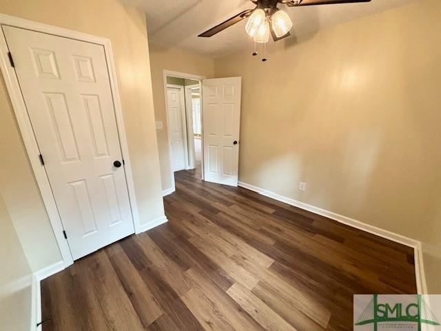 unfurnished bedroom with ceiling fan, dark hardwood / wood-style flooring, and a closet