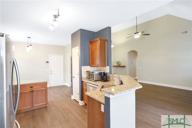 kitchen featuring stainless steel refrigerator, light stone counters, kitchen peninsula, and light wood-type flooring