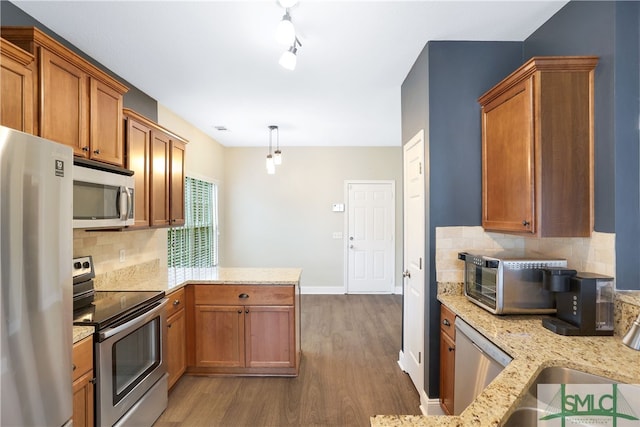 kitchen featuring dark wood-type flooring, tasteful backsplash, decorative light fixtures, kitchen peninsula, and stainless steel appliances