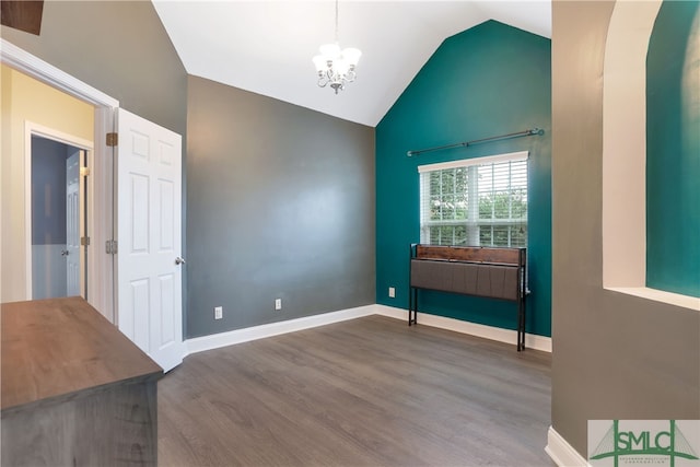 unfurnished room featuring hardwood / wood-style floors, lofted ceiling, and a notable chandelier