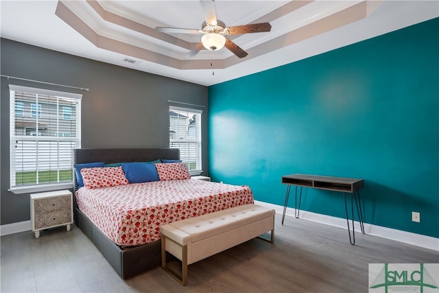 bedroom with a tray ceiling, ceiling fan, crown molding, and wood-type flooring