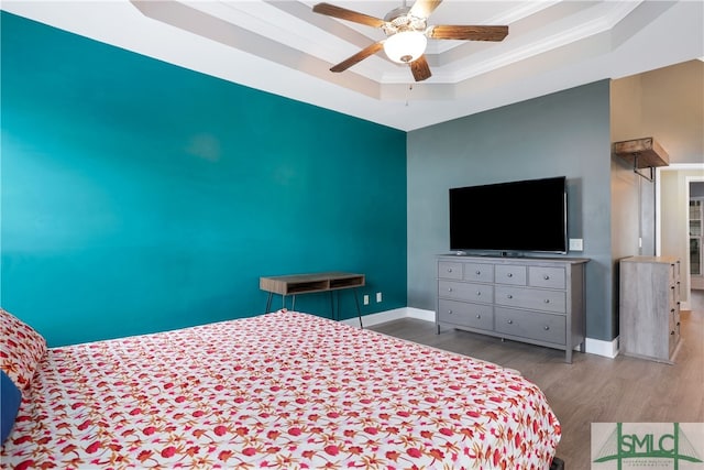 bedroom featuring ceiling fan, light hardwood / wood-style floors, a raised ceiling, and ornamental molding