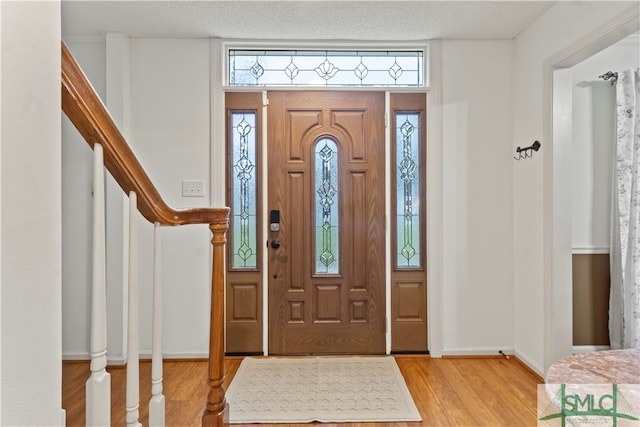 foyer entrance with a textured ceiling, light hardwood / wood-style floors, and a wealth of natural light