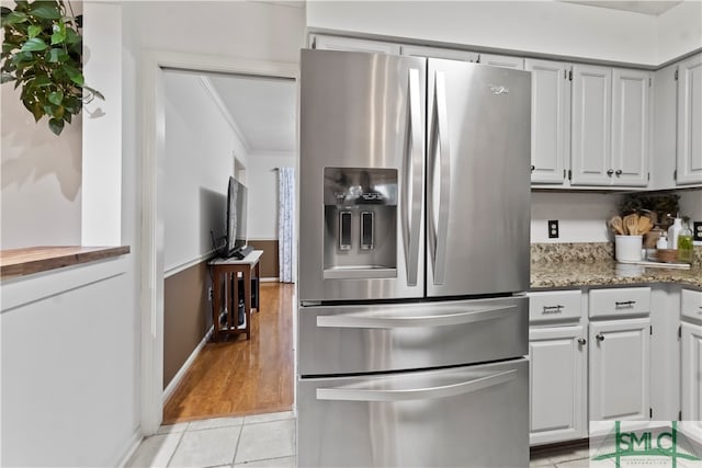 kitchen featuring white cabinetry, dark stone countertops, stainless steel fridge with ice dispenser, and light hardwood / wood-style flooring