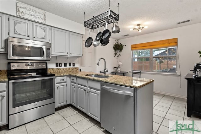 kitchen featuring gray cabinetry, sink, kitchen peninsula, a textured ceiling, and appliances with stainless steel finishes