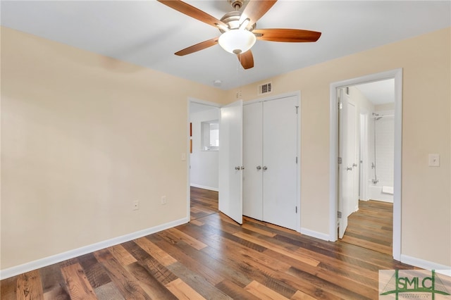 unfurnished bedroom with ceiling fan, dark wood-type flooring, and a closet