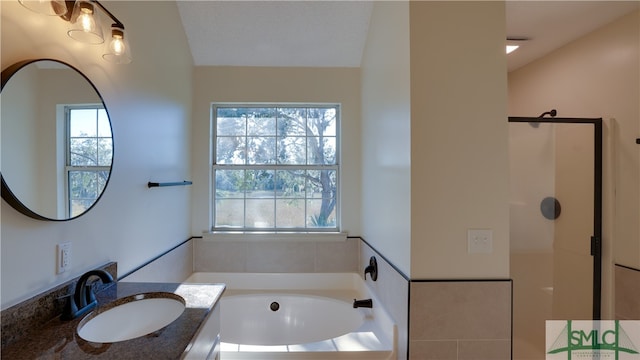 bathroom featuring vanity, a healthy amount of sunlight, lofted ceiling, and a textured ceiling