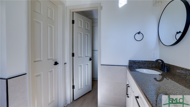 bathroom with vanity, wood-type flooring, and tile walls