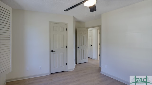 unfurnished bedroom featuring ceiling fan, light hardwood / wood-style floors, and a textured ceiling