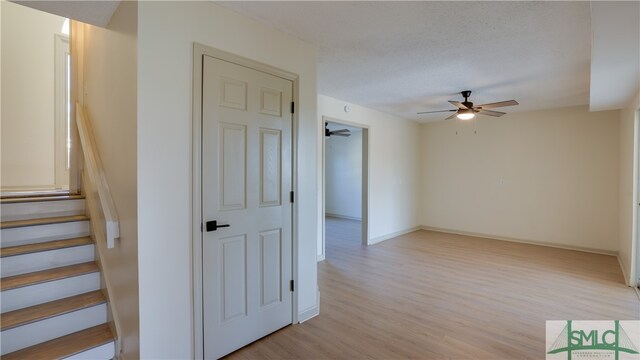 stairway featuring hardwood / wood-style flooring, ceiling fan, and a textured ceiling