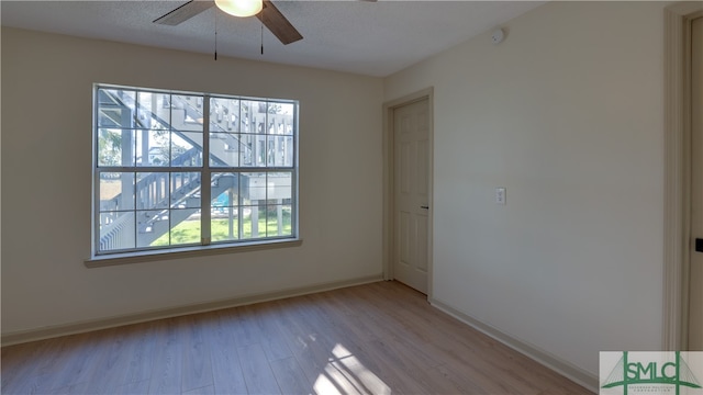 spare room with plenty of natural light, ceiling fan, light wood-type flooring, and a textured ceiling