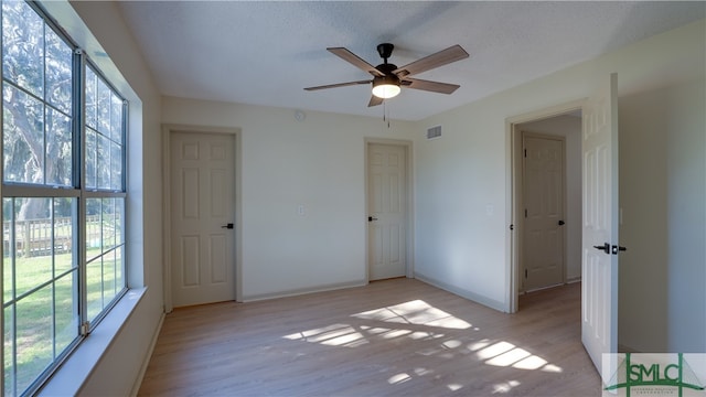 unfurnished bedroom with a textured ceiling, light wood-type flooring, and ceiling fan