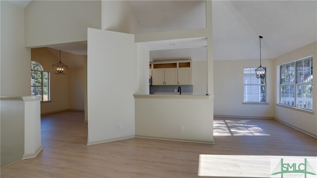 interior space with light wood-type flooring, a healthy amount of sunlight, and a notable chandelier