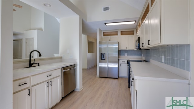 kitchen with sink, stainless steel appliances, tasteful backsplash, light hardwood / wood-style floors, and white cabinets