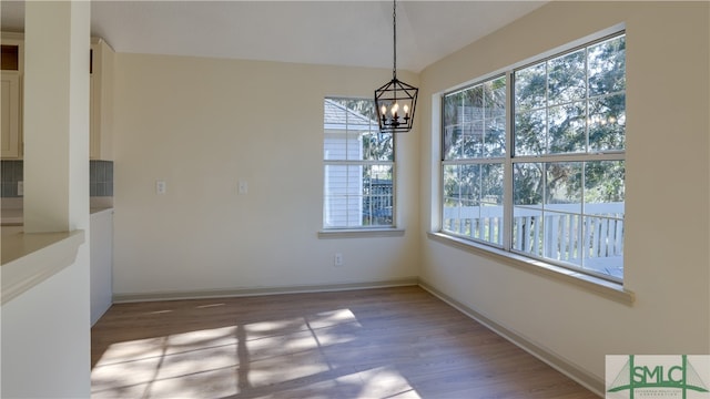 unfurnished dining area with a chandelier, a wealth of natural light, and light hardwood / wood-style floors