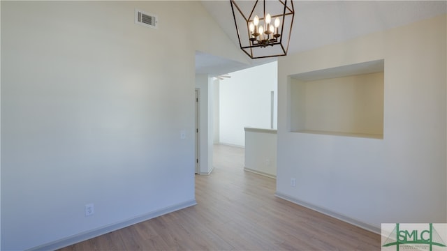 unfurnished room featuring light hardwood / wood-style floors, vaulted ceiling, and an inviting chandelier