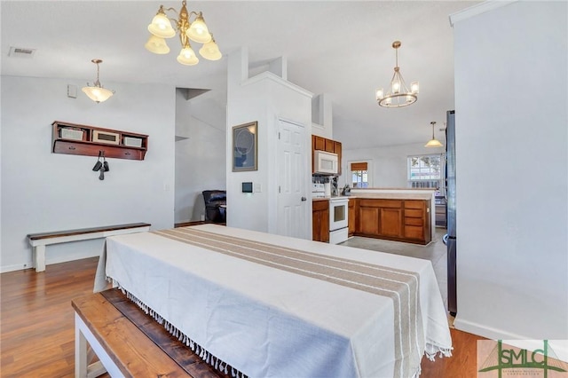 bedroom featuring lofted ceiling, light hardwood / wood-style flooring, and a notable chandelier